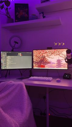 two computer monitors sitting next to each other on top of a desk in front of a purple wall