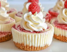 several cupcakes with whipped cream and raspberries on top are shown here