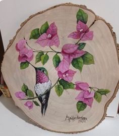 a bird sitting on top of a tree stump with flowers painted on it's side