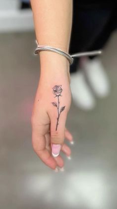 a woman's hand with a small rose tattoo on her left thumb and wrist