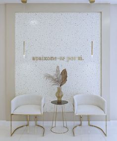 two white chairs sitting next to each other in front of a wall