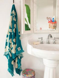 a white sink sitting under a bathroom mirror next to a green and white towel hanging on the wall