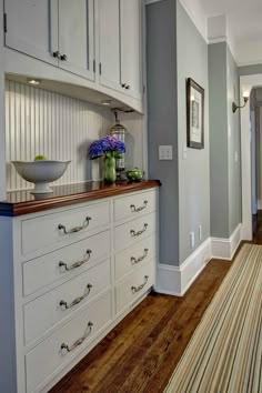 an image of a kitchen with white cabinets and wood flooring on the bottom row