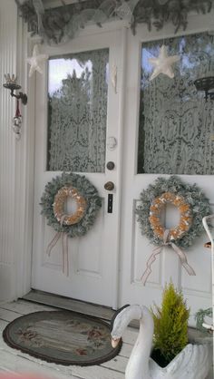 two wreaths on the front door of a house with swans and starfish decorations