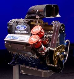 an engine on display in front of a blue background with the words ford racing written on it