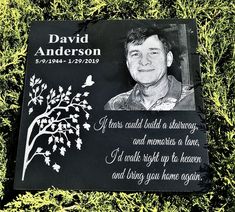 a memorial plaque with a photo of a man and a tree on it in the grass