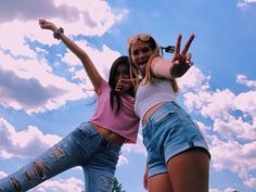 two young women standing next to each other with their hands in the air