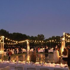 an outdoor wedding reception at night with string lights