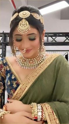 a woman in a green sari with gold jewelry