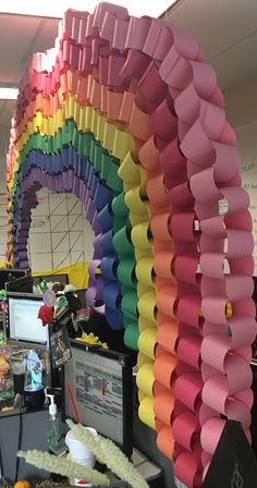 an office cubicle decorated in rainbow colors with paper decorations on the wall and desks