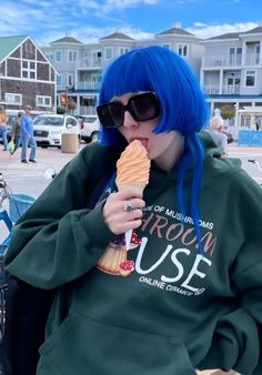 a woman with blue hair eating an ice cream cone