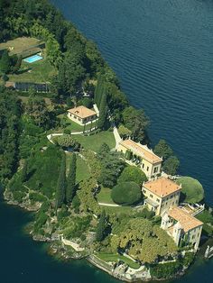 an aerial view of a large house in the middle of a body of water with trees around it