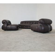 a brown leather couch and chair sitting next to each other in a room with white walls