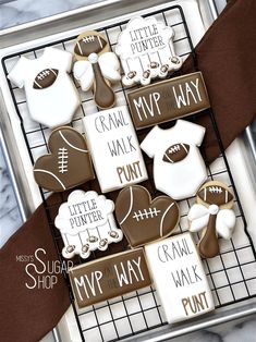 cookies decorated like footballs and other sports related items on a cookie sheet with brown ribbon