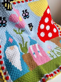 a crocheted blanket with animals and flowers on it