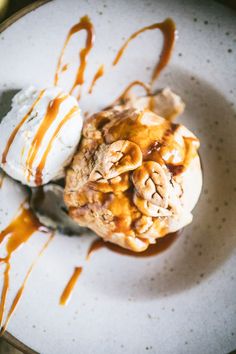 an ice cream sundae on a white plate with caramel drizzle