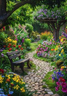 a garden filled with lots of flowers next to a wooden bench on a stone path