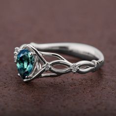 A handmade Celtic style platinum ring set with a beautiful, pear shaped Montana sapphire and small accent diamonds. The center stone is a 5mmX7mm natural Montana teal sapphire of high quality. Please note that the sapphires are natural stones and the exact shade may vary. The smaller stones are natural diamonds with a total carat weight of 0.06ct The ring is made with any of the available metals you select. All of the metals we use are 100% recycled. If you have any questions please feel free to Teardrop Sapphire Ring With Accent Stones For Anniversary, Pear-shaped Sapphire Promise Ring With Prong Setting, Fine Jewelry Sapphire Ring With Teardrop Prong Setting, Fine Jewelry Sapphire Teardrop Ring With Prong Setting, Teardrop Sapphire Ring With Diamond And Prong Setting, Sapphire Pear Shaped Rings For Anniversary, Sapphire Teardrop Ring With Prong Setting, Pear Shaped Sapphire Rings For Anniversary, Teardrop Emerald Ring With Diamond Prong Setting