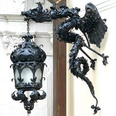 an ornate light fixture hanging from the side of a building with intricate carvings on it