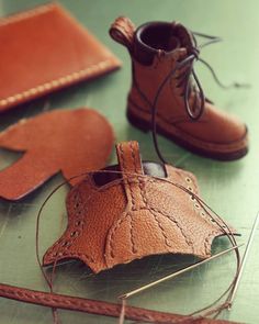 a pair of brown shoes sitting on top of a table next to a piece of leather