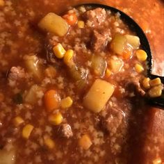 a spoon full of soup with corn and meat