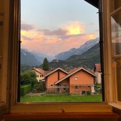 an open window with the view of mountains and houses in the foreground, at sunset