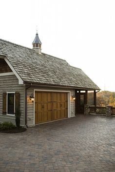 a house with a large driveway and two garages on each side, surrounded by brick pavers