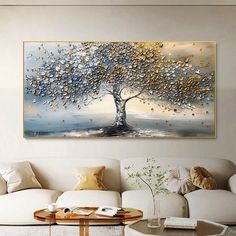 a living room with white couches and paintings on the wall, including a painting of a tree