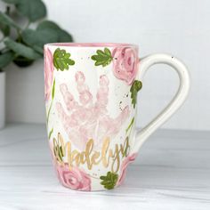 a handprinted coffee mug with pink roses on it and the words make joy written in gold