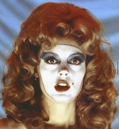 a woman with white makeup and red hair