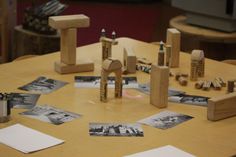 a wooden table topped with lots of pictures and pencils on top of it's sides