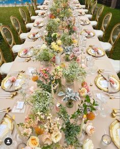 a long table is set with flowers and place settings for an elegant dinner party in the garden