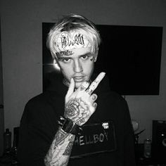 a man with tattoos on his face and fingers making the peace sign in front of him