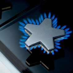 a close up view of a stove with blue flames and an arrow on the burner