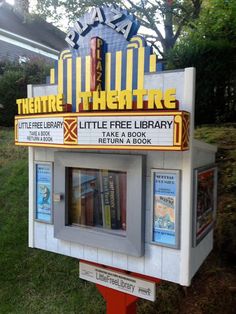 there is a little free library sign in front of the theater theatre on the street