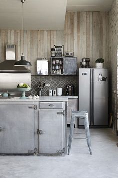 an industrial kitchen with stainless steel appliances and wood paneling on the wall behind it