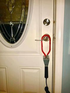 a door handle is attached to a white door with a red leash hanging from it's side