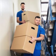 two men in blue shirts carrying cardboard boxes