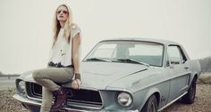 a woman sitting on the hood of an old mustang