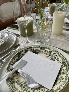 a table set with place settings and flowers in vases, candles and napkins