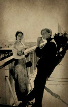 an old black and white photo of two people standing on a balcony looking at the camera