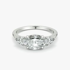 three stone diamond ring in 18k white gold with four stones on the band and an oval