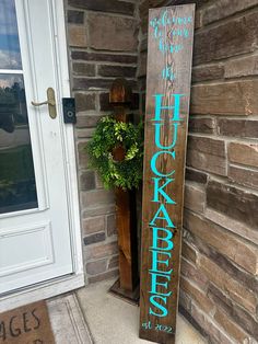 a wooden sign sitting outside of a brick building next to a potted green plant