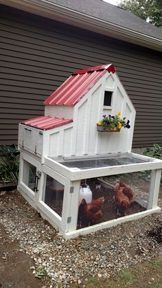 a chicken coop with flowers in the window and stuffed animals on the ground next to it