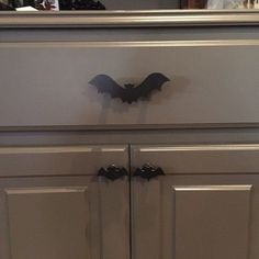 a bat shaped drawer pulls are on the top of a gray cabinet in a kitchen