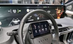 the interior of an electric vehicle with touchscreens and steering wheel controls on display