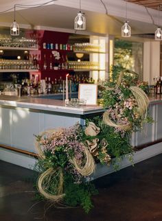 the bar is decorated with flowers and greenery for an elegant touch to the space