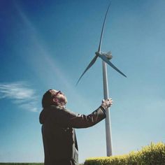 a man standing next to a wind turbine