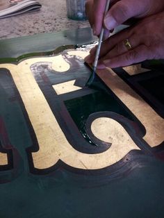 a person is painting the letters in gold and green