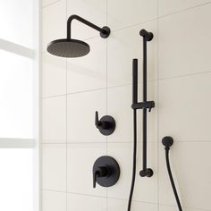 a black shower head and handset in a white tiled bathroom